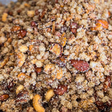 A close-up view of a textured mixture of brown sugar, chopped nuts, and dried fruit pieces piled in a container.